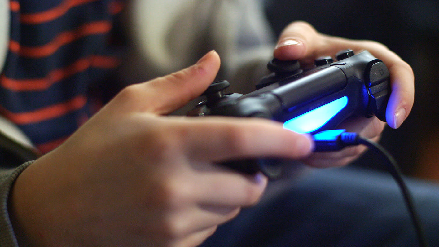 Nahaufnahme zweier Hände, die einen beleuchteten Spielecontroller halten