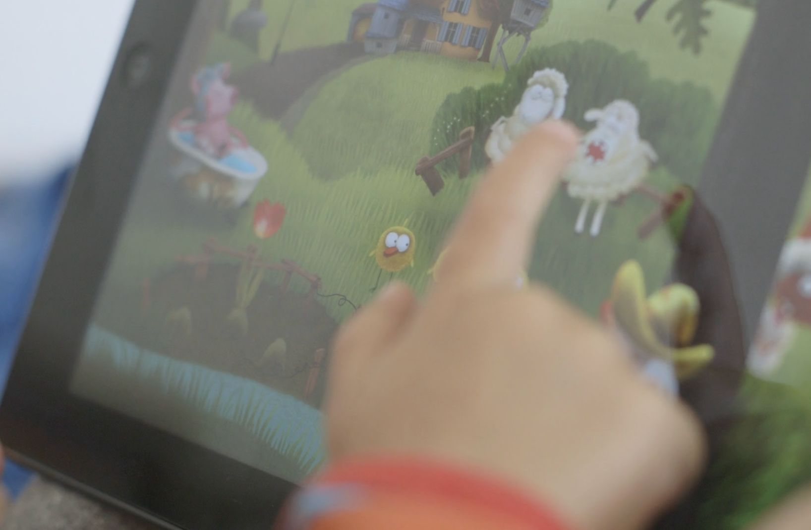 Ein Kind tippt auf ein Tablet mit einer animierten Bilderbuch-App voller Tiere