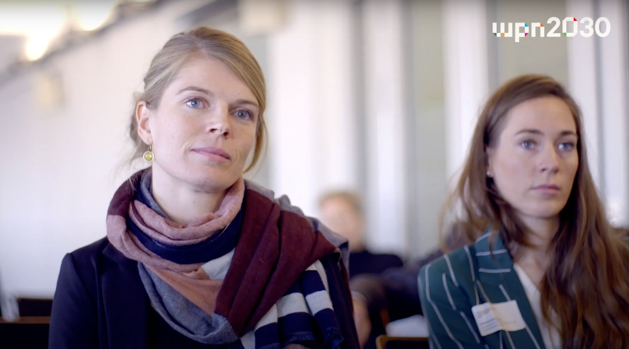 Zwei Frauen sitzen aufmerksam im Publikum einer Veranstaltung