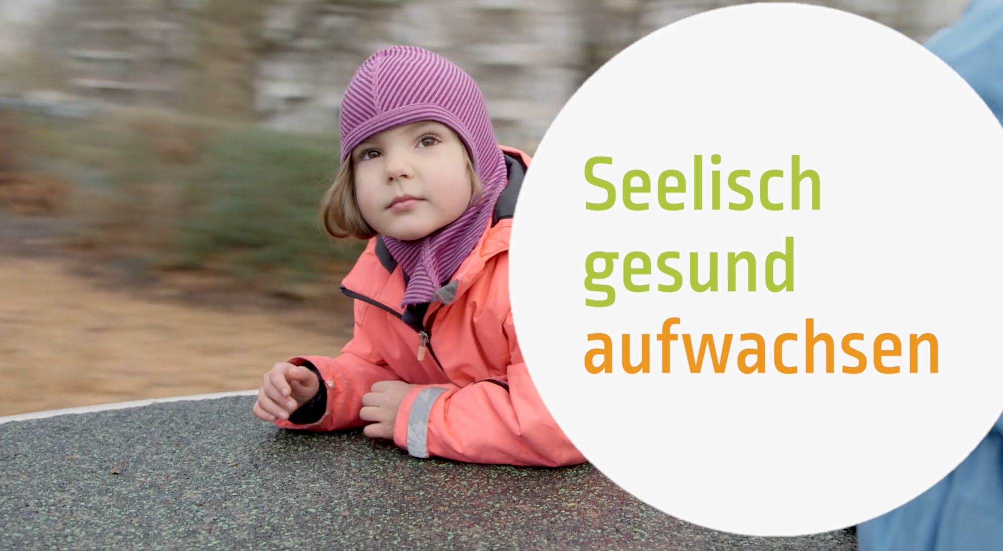 Mädchen mit lila Mütze lehnt an einer Mauer, Titelkarte „Seelisch gesund aufwachsen“