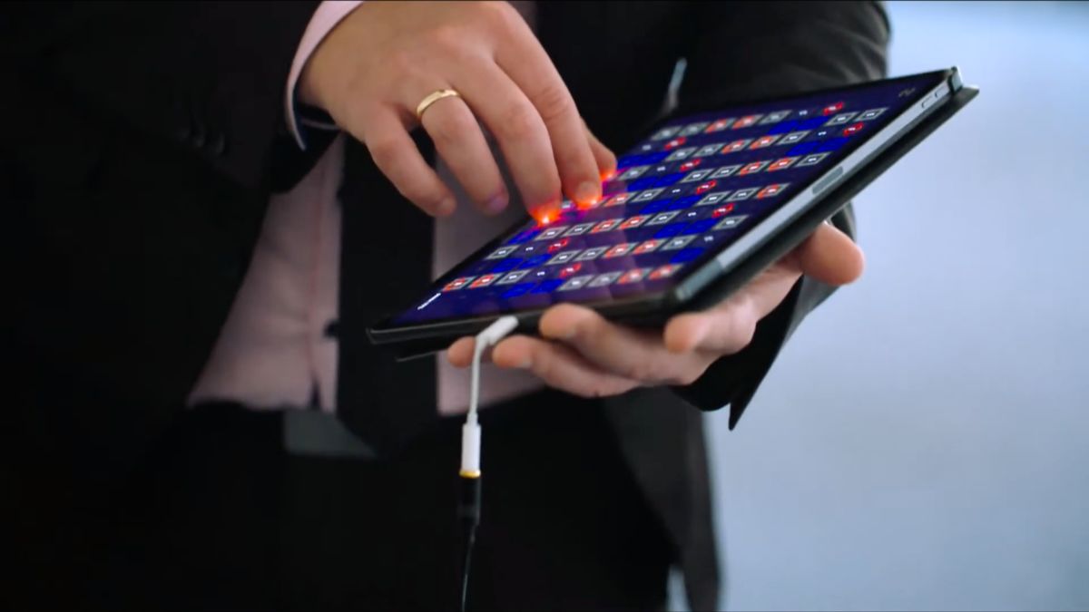 Hand mit Ring bedient ein tragbares Gitter-Musikinstrument mit bunt leuchtenden Feldern