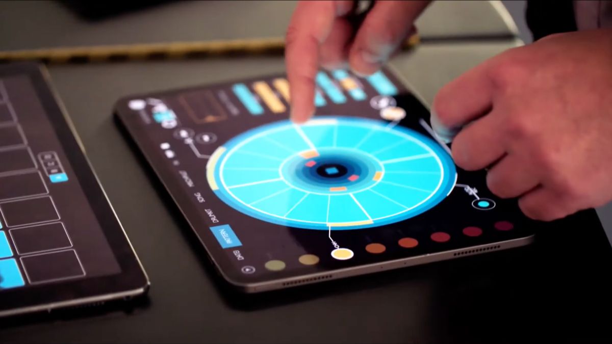 Zwei Hände bedienen ein rundes, blau leuchtendes Regler-Interface auf einem Tablet