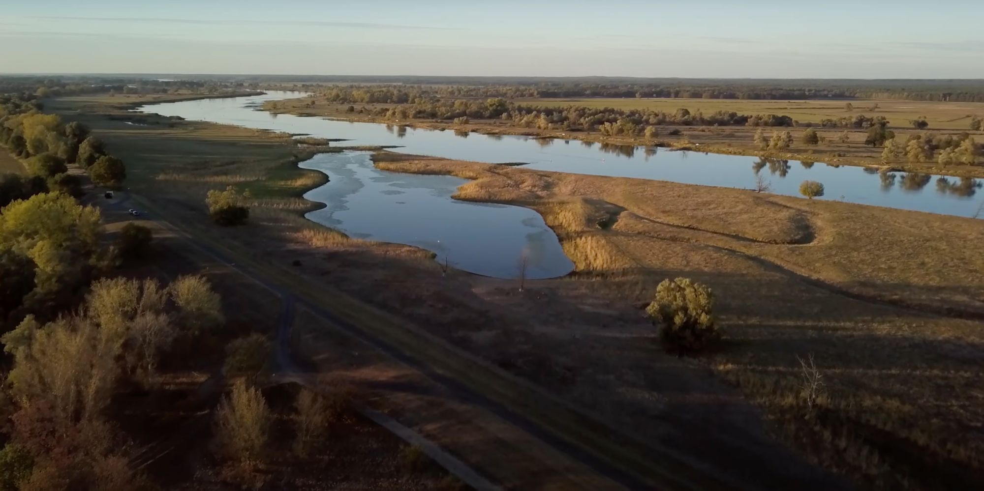 Luftaufnahme der Oderbruch-Landschaft mit gewundenem Fluss, Wiesen und Feldweg