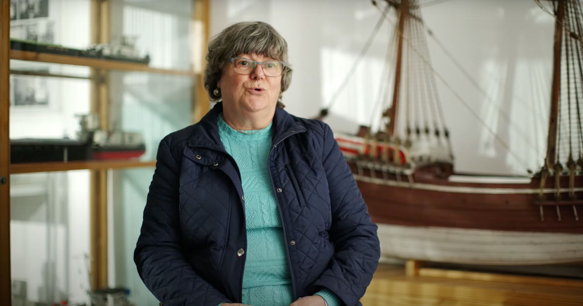 Frau im Gespräch vor Museumsvitrinen mit historischen Schiffsmodellen