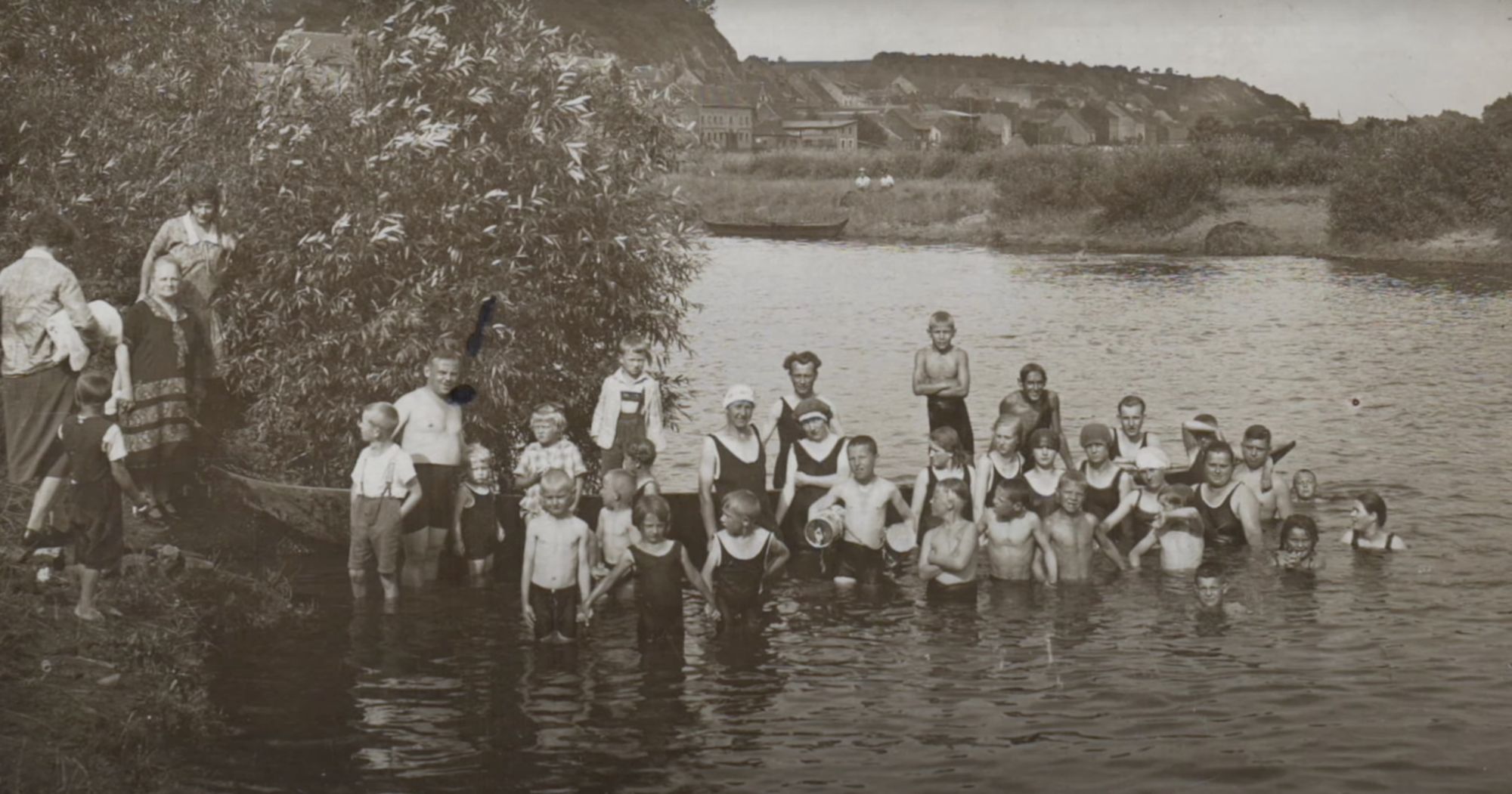 Historisches Foto: badende Kinder und Erwachsene am Flussufer im Schilf