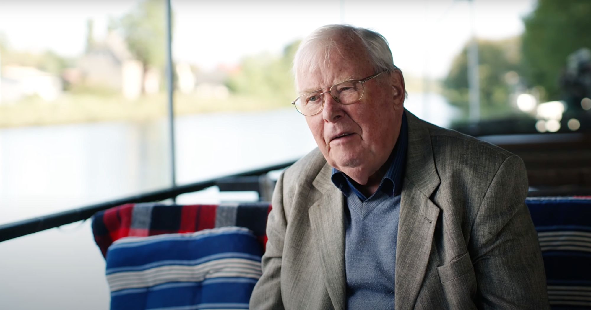 Älterer Mann im Gespräch an Bord eines Schiffes vor der Flusslandschaft