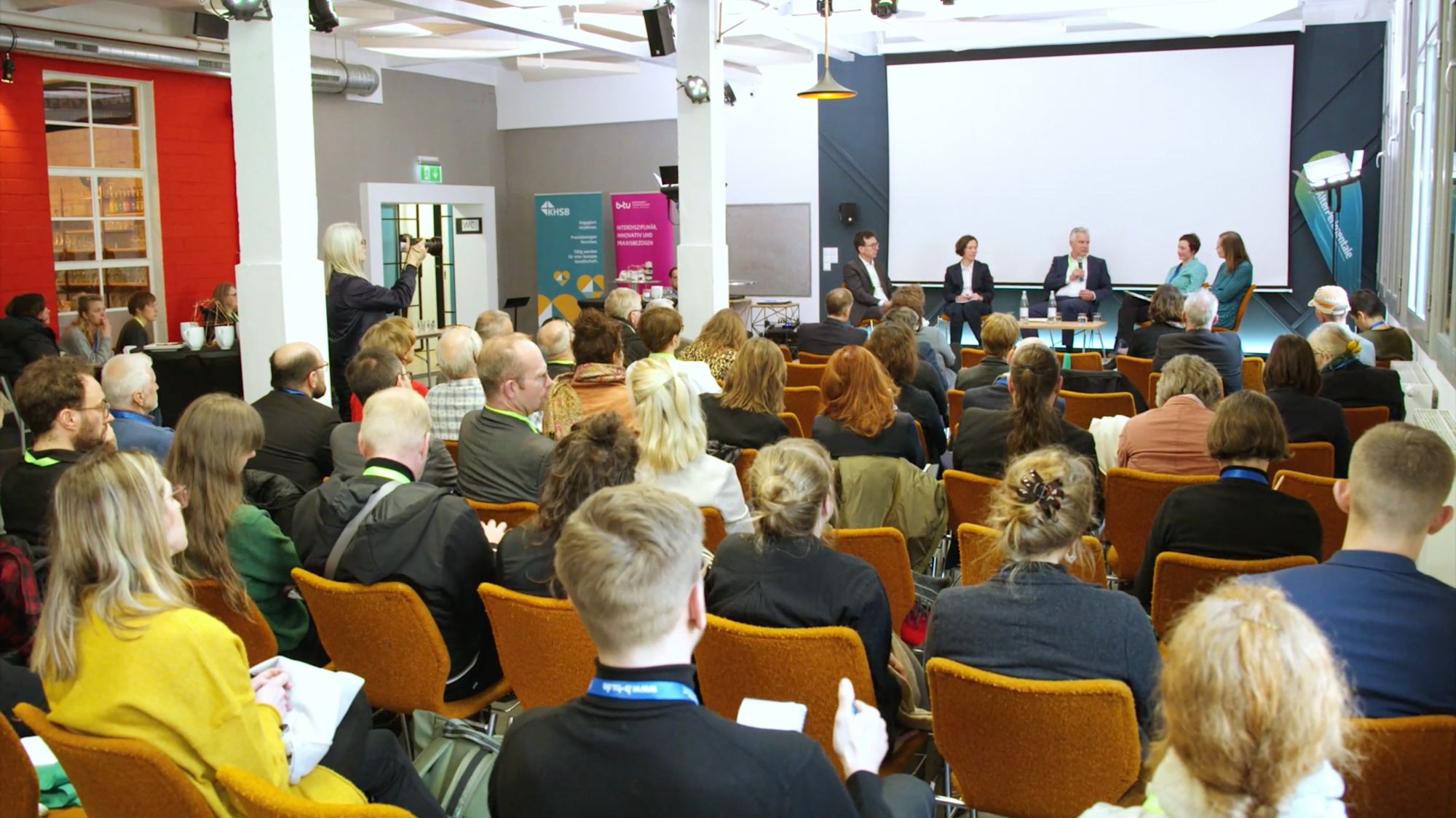 Panel discussion in front of a large audience in an event hall