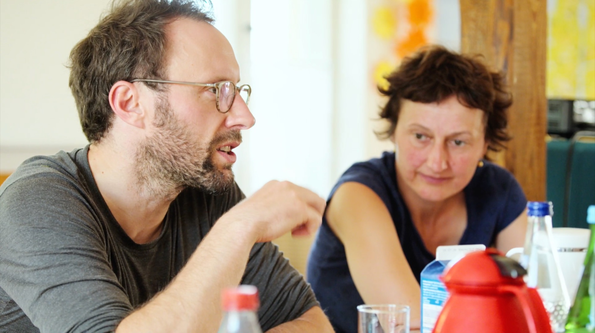A man in conversation with a woman at a table with drinks