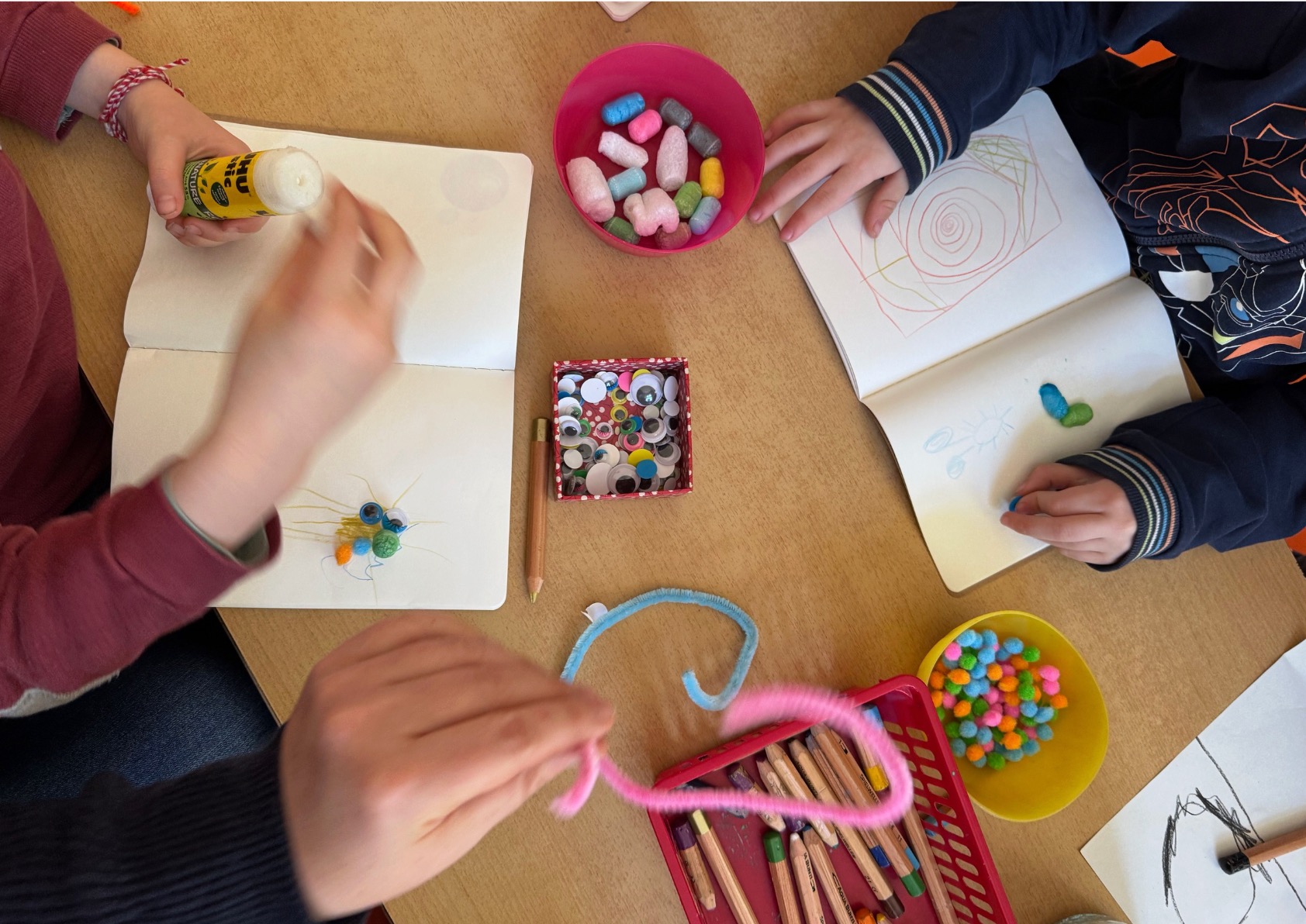 Children at a table crafting colourful microbe figures from googly eyes and pipe cleaners