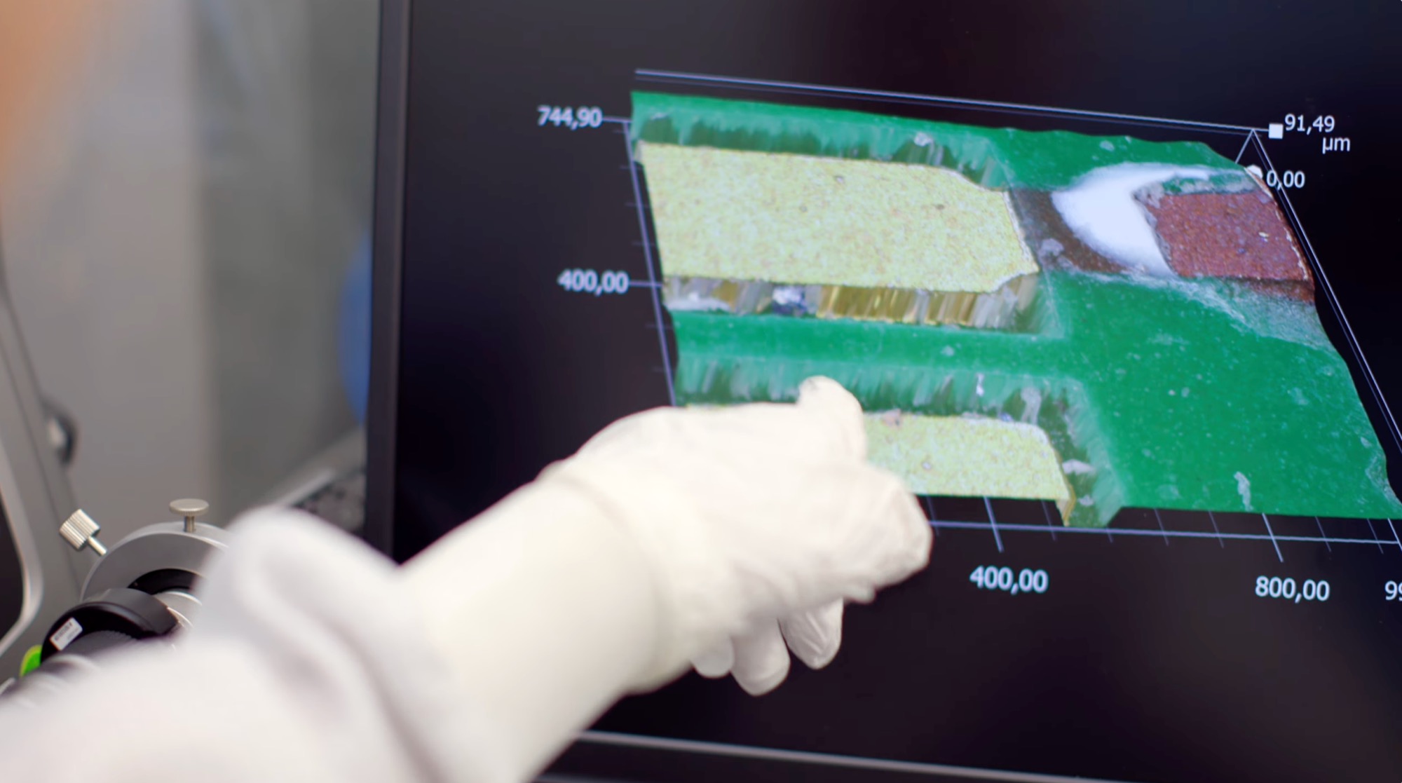 A gloved hand points to a scientific 3D data visualisation on a screen